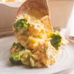 a spoonful of broccoli cheddar casserole being put on a plate