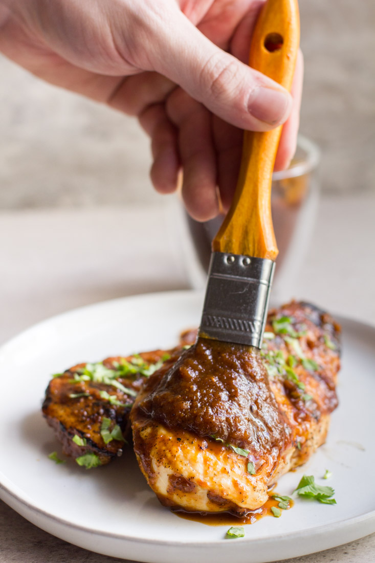 plate with chicken being brushed with bbq sauce
