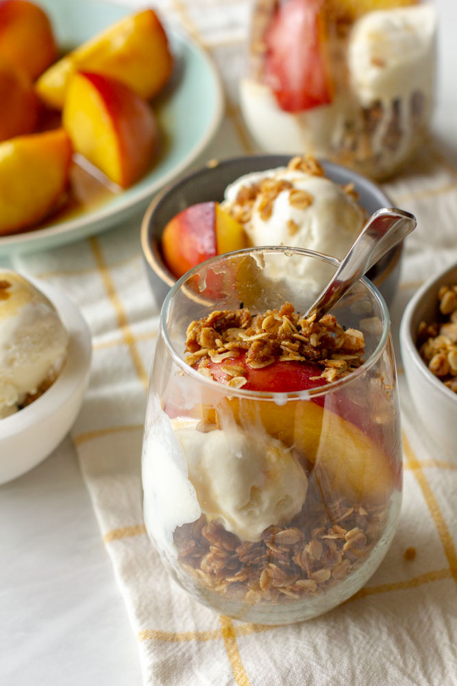 peach sundae on a table with honey, ice cream and toasted oats