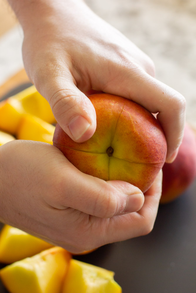 hands holding a peach and twisting apart