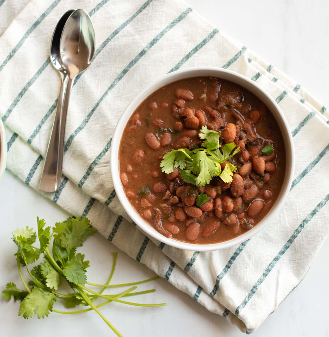 Instant Pot Charro Beans in a white bowl with cilantro on top