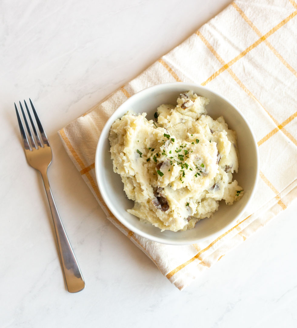 a top down view of instant pot mashed potatoes in a white bowl on a white table