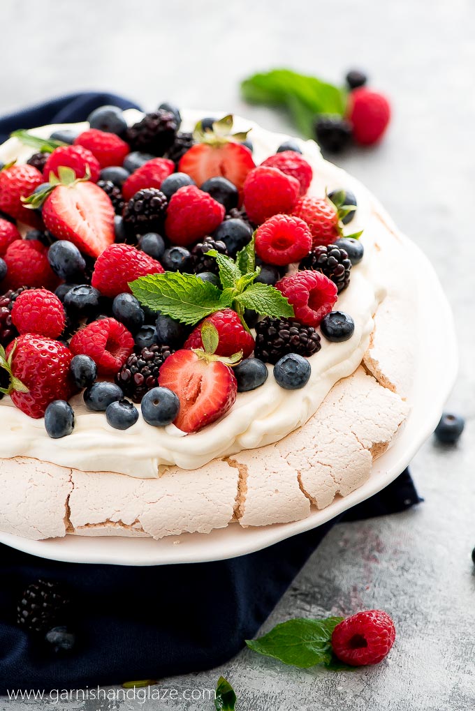 mixed berry pavlova with raspberries, strawberries and blueberries on a white background