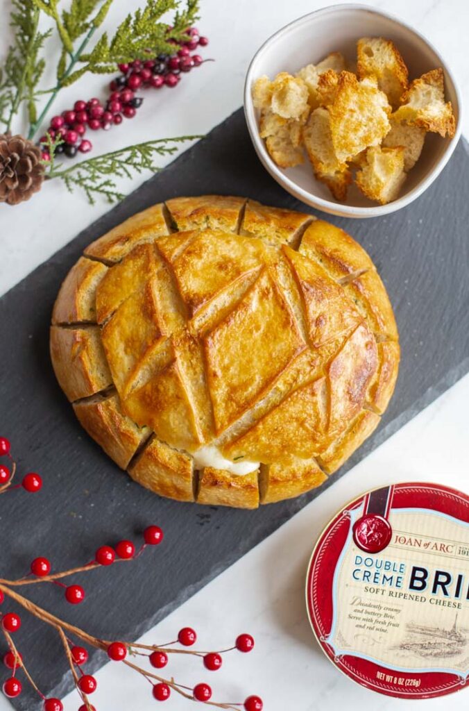baked brie with cranberries with the edges cut into a pull apart bread