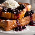 A delicious brioche french toast stuffed with blueberry cream cheese and topped with blueberry syrup. It's a gorgeous dish that makes breakfast extra special!
