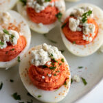 buffalo deviled eggs on a plate topped with blue cheese