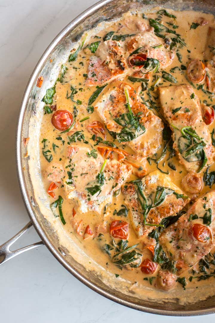 pan seared salmon with spinach and tomatoes in a skillet