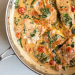 Pan seared salmon served in a creamy sauce with garlic, spinach and tomatoes. It's an easy weeknight meal and a delicious seafood dish to serve at your next dinner party!