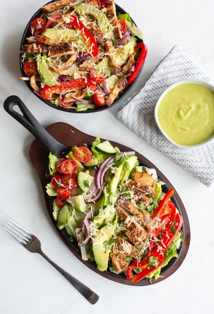 grilled chicken fajita salad on a plate with avocado lime dressing on the side