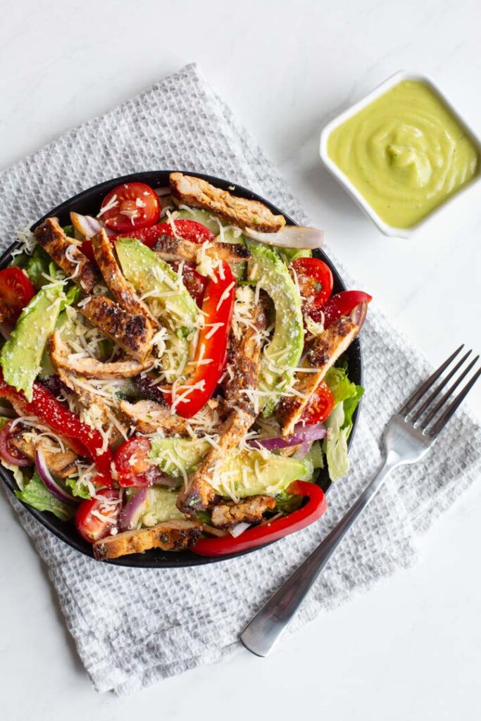 grilled chicken fajita salad with peppers, onions, avocado, tomatoes and cheese