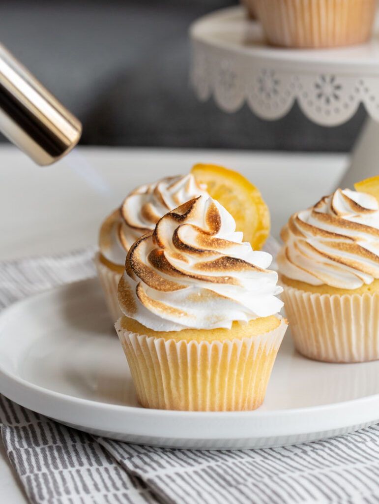 lemon meringue cupcakes being charred by a culinary torch