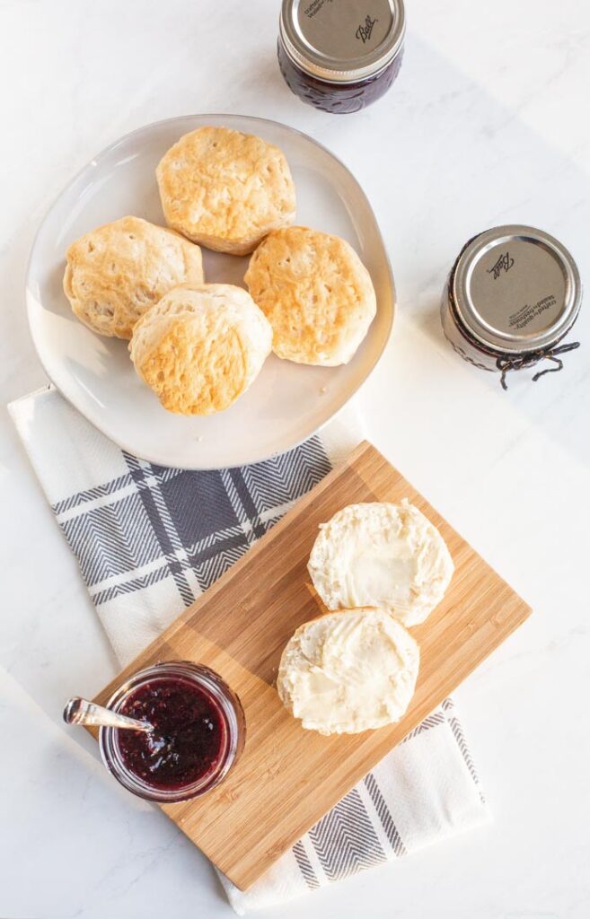 a plate of biscuits with a jar of mixed berry jam