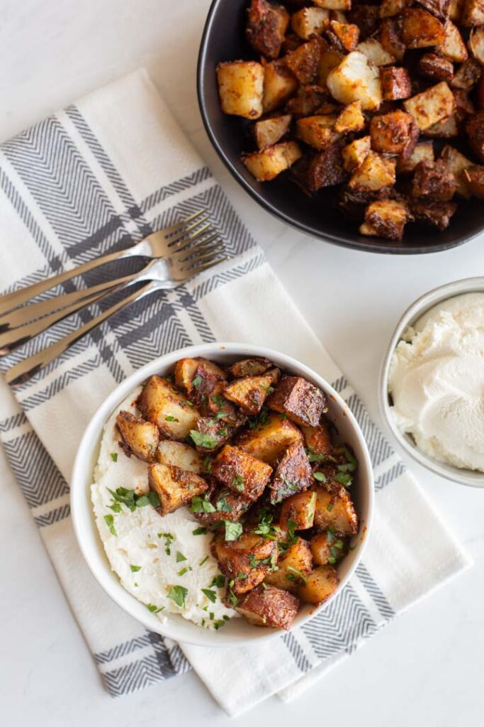 spicy roasted potatoes in a bowl with ricotta cheese and honey