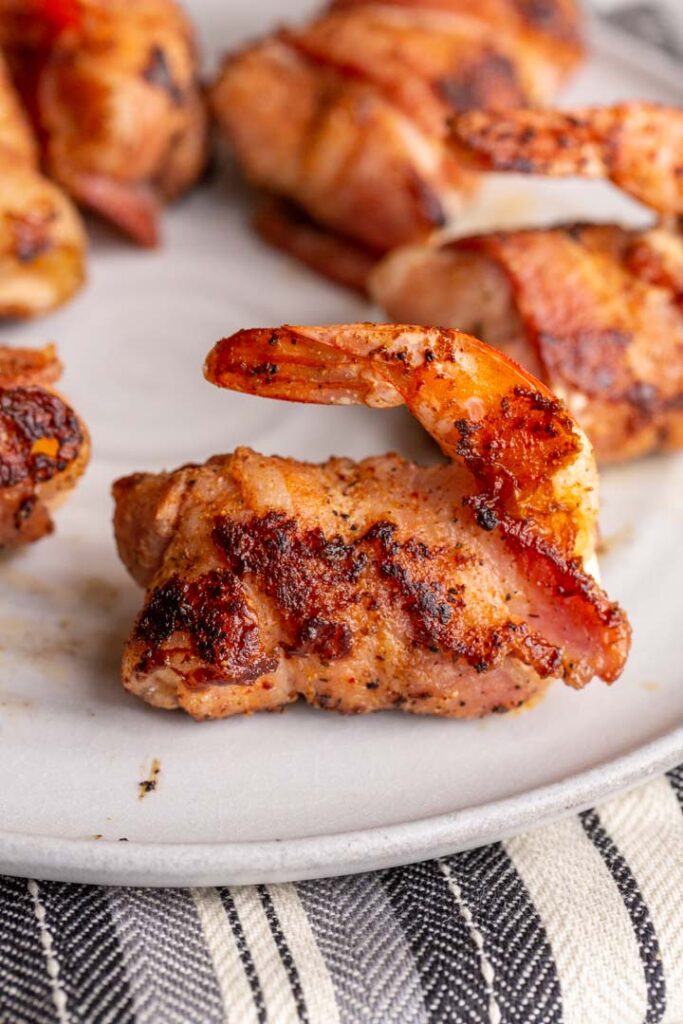 stuffed shrimp en brochette on a plate, wrapped in bacon