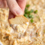 hot crab dip being scooped up with a crisp