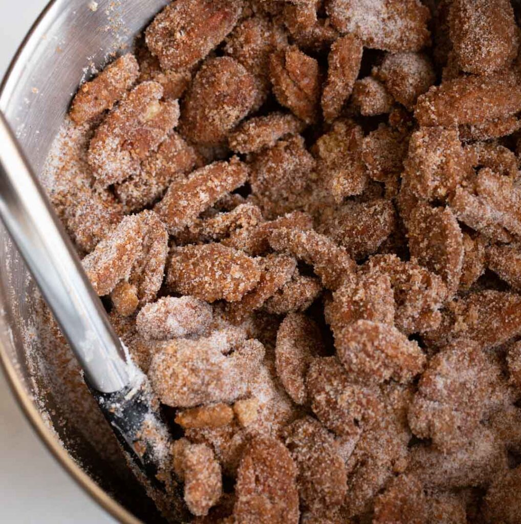 pecans in a bowl tossed with cinnamon sugar spice mix