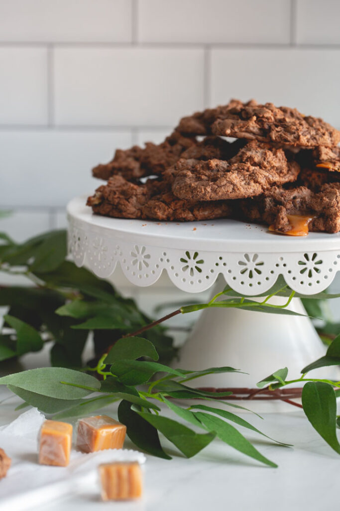 chocolate cookies with caramel and pecans on a stand