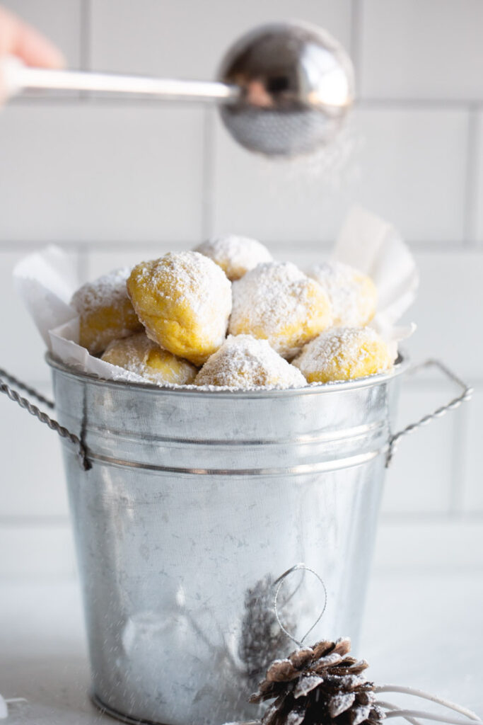 lemon snowball cookies being dusted with powdered sugar