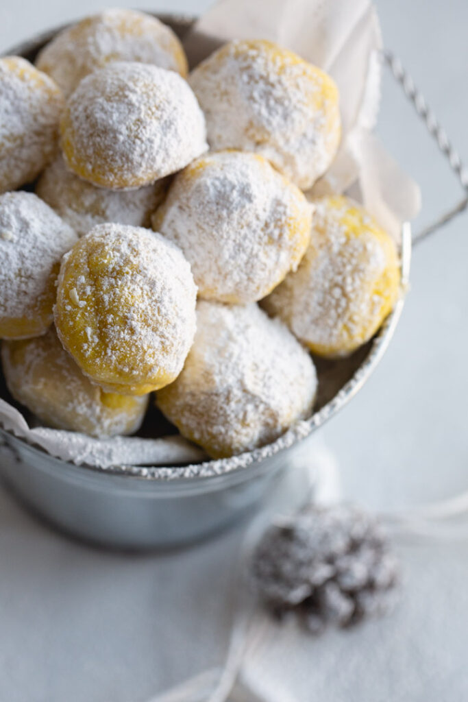 lemon snowball cookies in a tin with parchment