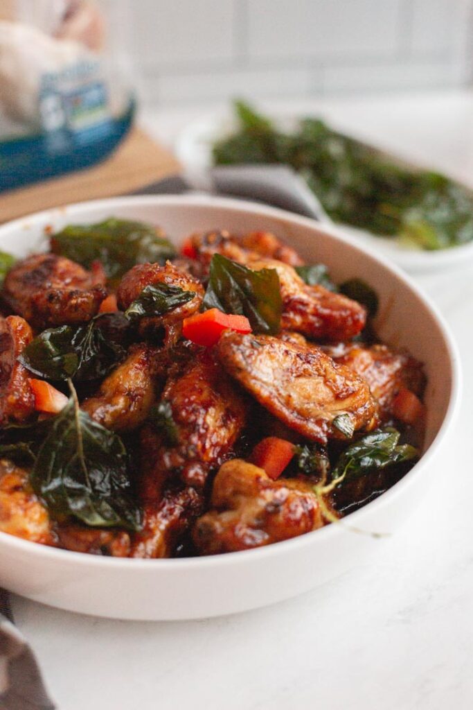 crispy garlic chicken wings in a bowl garnished with fried basil and red pepper