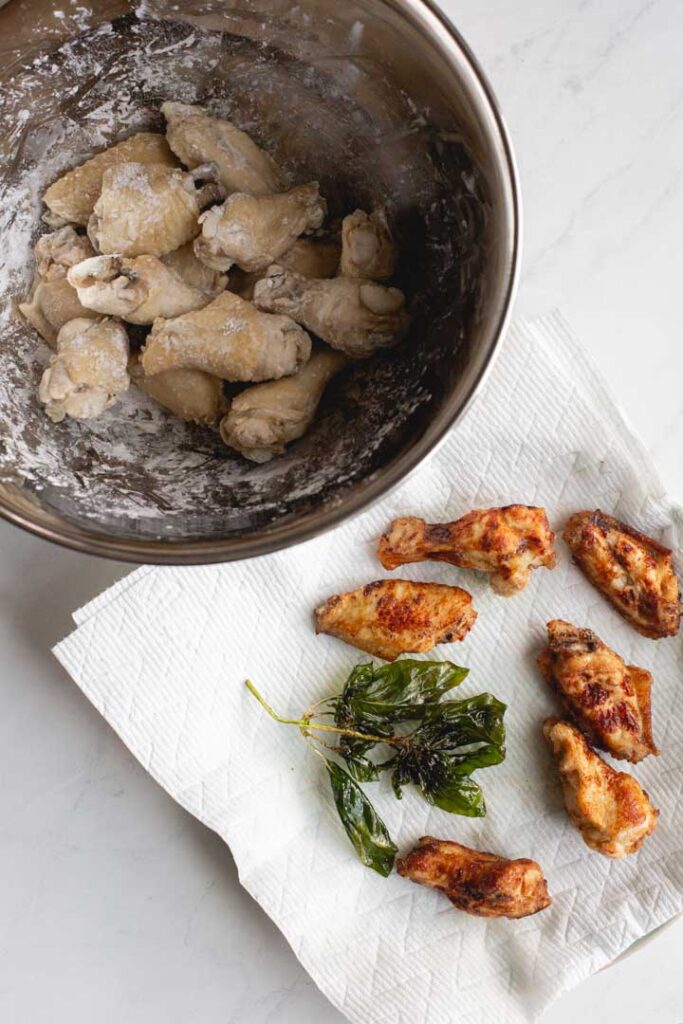chicken wings in a bowl with tapioca starch and finished fried wings on the side