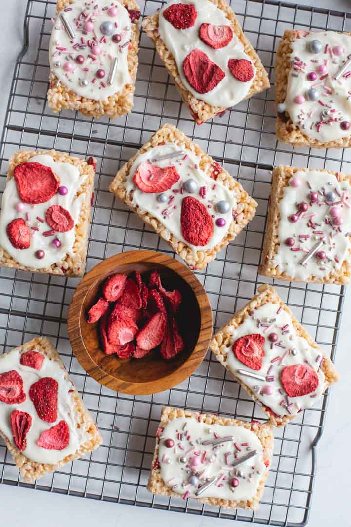 strawberry rice krispie treats on a rack topped with white chocolate and sprinkles