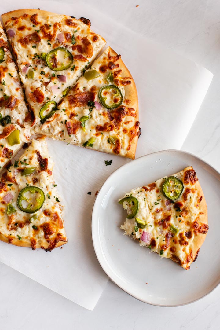 bacon and crab pizza on a table with one slice taken away and put on a plate