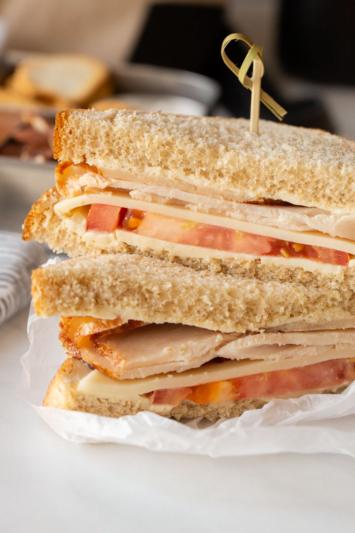 turkey and swiss cheese sandwich stacked on a paper and fastened with a toothpick