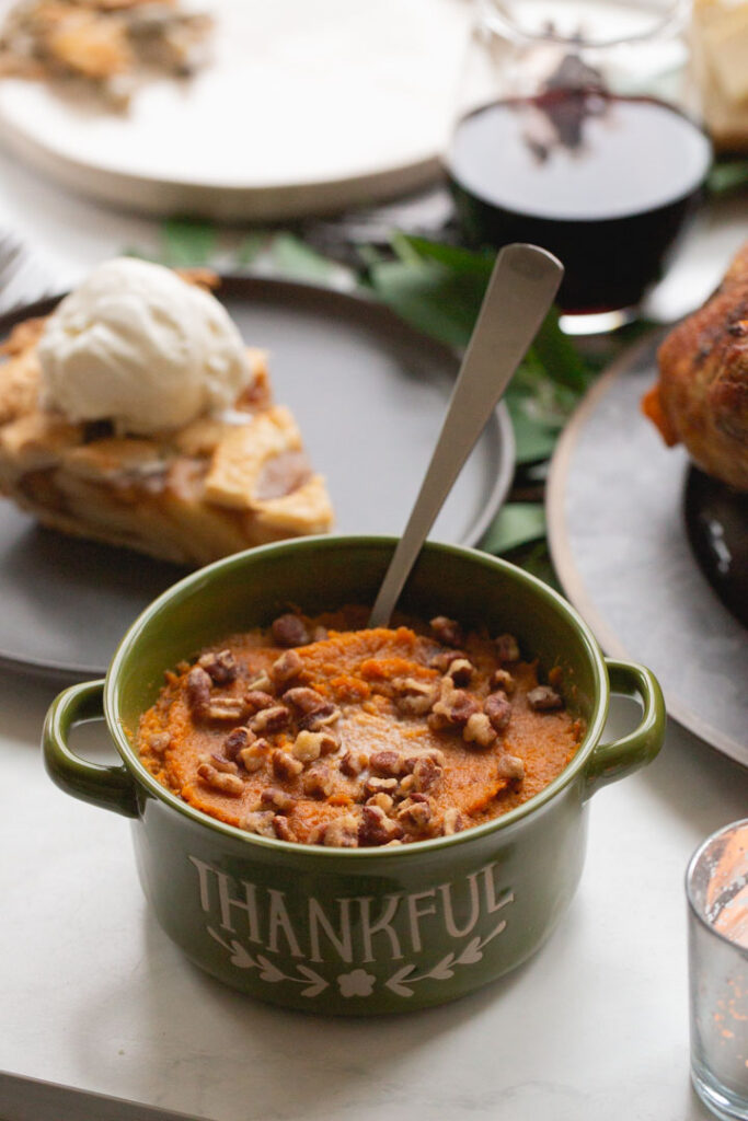 bourbon sweet potatoes in a serving dish with candied pecans on top